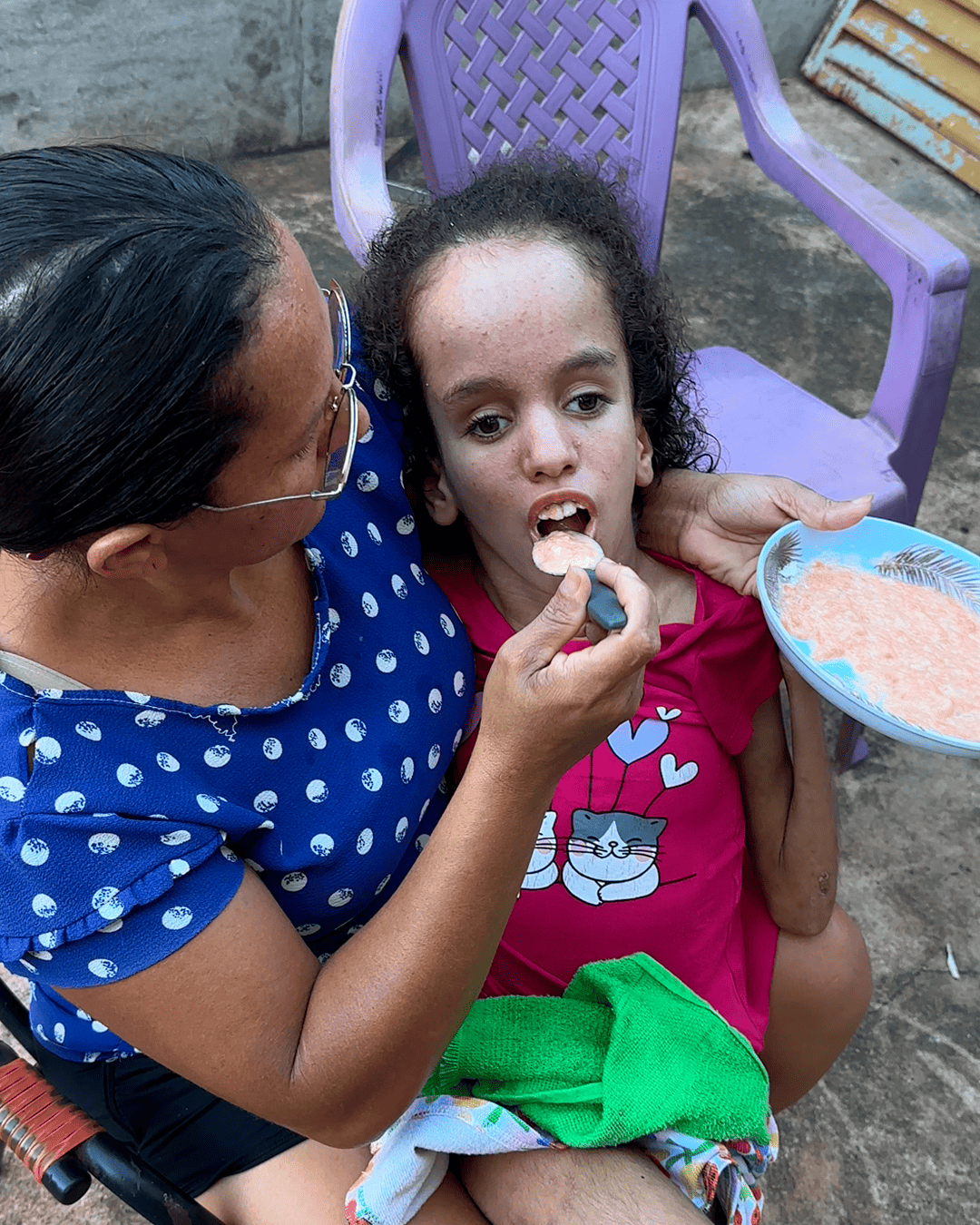 Maria Sônia alimentando Ana Júlia no colo